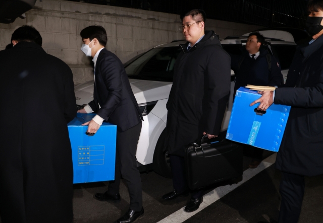 Investigators load confiscated items and forensic equipment into a vehicle after leaving the presidential office in Yongsan, Seoul, Wednesday. (Yonhap)