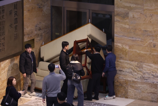 Democratic Party of Korea staffers barricade an entrance with furniture in an attempt to block soldiers from getting in early Wednesday. (Yonhap)